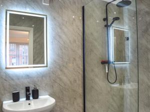 a bathroom with a shower and a sink and a mirror at West Street House in Southport