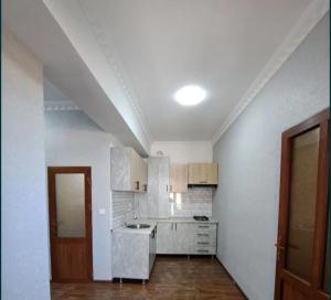 cocina con paredes blancas y suelo de madera en Guesthouse Anora en Samarcanda