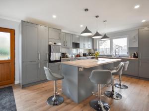 a kitchen with gray cabinets and a island with bar stools at Fircroft in Glencarse