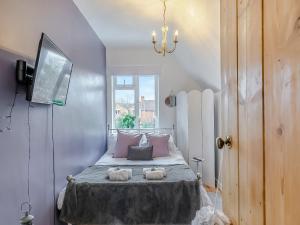 Un dormitorio con una cama con almohadas rosas y una ventana en Crompton Cottage, en Bretforton