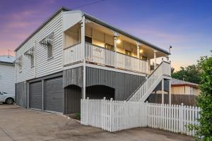 a house with a white fence in front of it at Spacious and Charming Queenslander in Ipswich in Bundamba