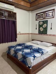 a bed with a blue and white comforter in a bedroom at Bagus Homestay in Padangbai