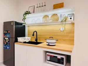 a kitchen with a counter with a sink and a refrigerator at Vinhomes Grand Park - FEBRUARYroom in Gò Công