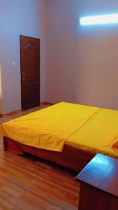 a bedroom with a bed with a yellow blanket on it at Timba OUEDO-VERDURE in Tokpa