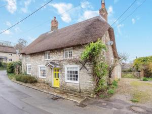 an old stone house with a yellow door at Jasmine Cottage in Osmington