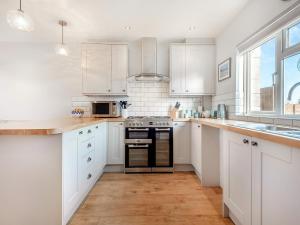 a kitchen with white cabinets and a stove top oven at Capston Cottage in Langton Matravers