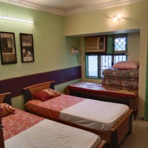 um quarto com 3 camas e uma janela em WISHTREE DORMITORY/CORPORATE DORMITORY FOR TECHIES AND TRAINEES em Chennai