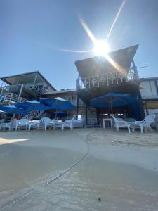 普拉亞布蘭卡的住宿－MAR AZUL ISLA BARU, RESTAURANTE HOTEL.，海滩上的一组椅子和遮阳伞