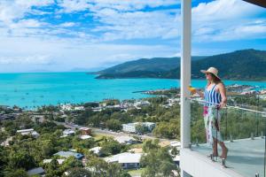 Una mujer parada en un balcón mirando el océano. en The View, en Airlie Beach