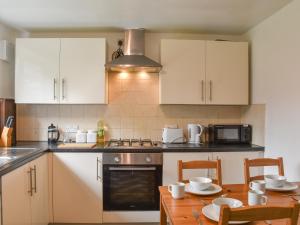 a kitchen with white cabinets and a wooden table at Wyndham House in Troed-y-rhiw