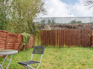 a chair and a table in a yard with a fence at Wyndham House in Troed-y-rhiw