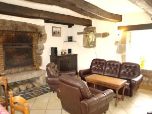 a living room with leather furniture and a stone fireplace at Maison de 3 chambres avec jardin amenage a Sibiril a 3 km de la plage in Sibiril