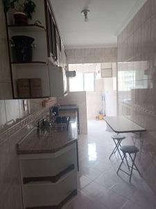 een keuken met een aanrecht en een tafel. bij Apartamento Guarujá Pitangueiras in Guarujá