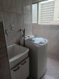 een badkamer met een toilet, een wastafel en een raam bij Apartamento Guarujá Pitangueiras in Guarujá