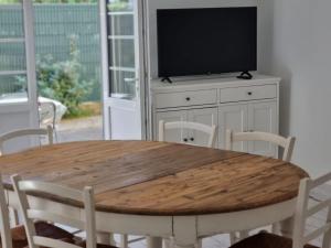 una mesa de madera con sillas y un armario blanco con TV. en Appartement Vieux-Boucau-les-Bains, 5 pièces, 8 personnes - FR-1-239-761, en Vieux-Boucau-les-Bains