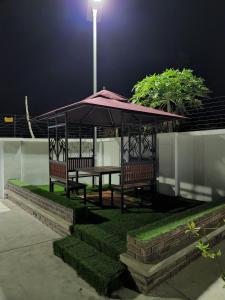a gazebo with two benches and a table at night at Samuel Court in Abuja