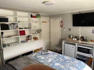 Habitación pequeña con mesa, TV y estanterías. en BBs B&B, en Lower Hutt