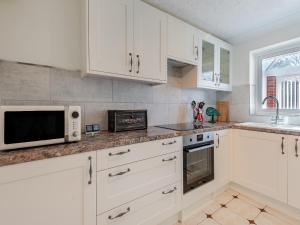 a kitchen with white cabinets and a microwave at Goose Green House in Sutton Bridge