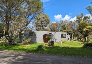 a white house with a red door in a yard at The Wannon 2 in Dadswells Bridge