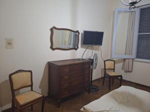 ein Schlafzimmer mit einer Kommode, 2 Stühlen und einem Spiegel in der Unterkunft Casona Harguindeguy in Paysandú