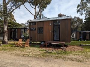 uma pequena casa com uma mesa de piquenique e cadeiras em Tiny House 11 at Grampians Edge em Dadswells Bridge