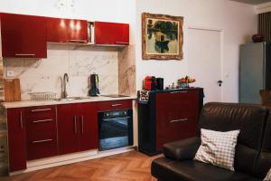 - une cuisine avec des placards rouges et un canapé dans la chambre dans l'établissement L'Alouette - Appartement 60m2 PMR, à Château-Thierry