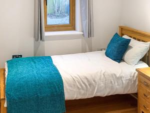 um quarto com uma cama com almofadas azuis e uma janela em Chestnut Lodge em Langley