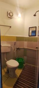 a bathroom with a toilet and a green bucket at Hostel Gandhi in Chennai