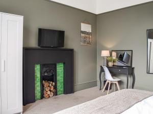 a bedroom with a fireplace with a tv above it at Main Street Flat A - Uk46448 in Ayr