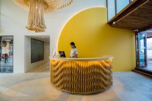 a woman sitting at a yellow counter in a lobby at Sea Sun Bed & Beyond in Koh Samui 