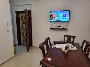 a dining room with a table and a television on a wall at Zemmouri 3 in Tangier