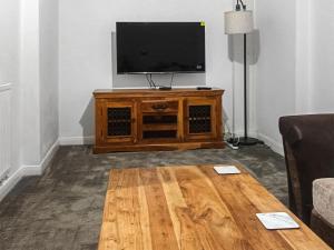 sala de estar con TV y mesa de centro de madera. en Cousens House en Dawlish