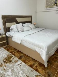 una camera da letto con un grande letto con lenzuola bianche di العلم نور a Sīdī Ḩamzah
