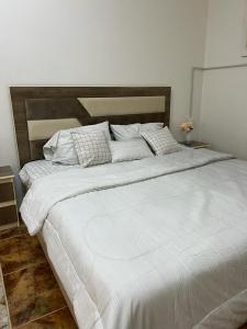 1 cama blanca grande con sábanas y almohadas blancas en العلم نور, en Sīdī Ḩamzah