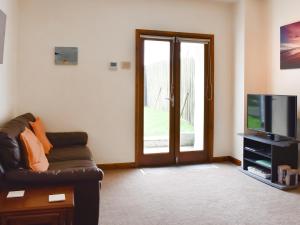 a living room with a couch and a television at Contention Barn in Perranporth