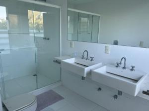 - une salle de bains blanche avec deux lavabos et une douche dans l'établissement Pousada Mansão Triplex Jolly, à Búzios