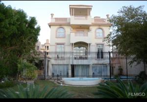 una casa grande con una valla delante en قصر 6غرف حمام سباحه en 6th Of October