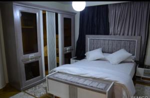 a bedroom with a white bed with two windows at قصر 6غرف حمام سباحه in 6th Of October
