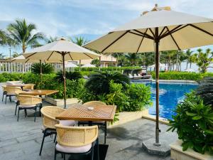 a patio with tables and umbrellas next to a pool at Wyndham Cam Ranh Villa 1412 in Cam Lâm