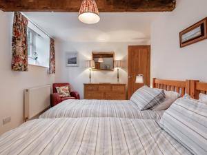 a bedroom with two beds and a red chair at Crosscombe Barn in Loddiswell