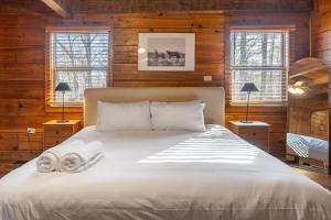 a bedroom with a white bed with two lamps and windows at Dudley II by AvantStay Comfortable Cabin w Hot Tub Views in Pigeon Forge