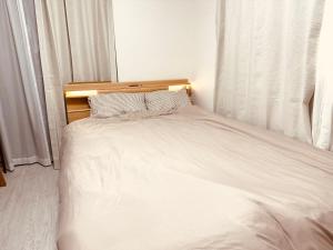 a bed with white sheets and pillows in a bedroom at Bon House Kanamachi Direct to Sensoji Skytree Disneyland Airport Free Parking Reservation Required in Tokyo