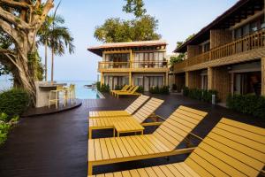 a deck with yellow benches and a building at Sea Sun Bed & Beyond in Koh Samui 