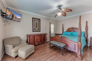 een slaapkamer met een bed, een stoel en een ventilator bij HavaGetaway Pool Spa BBQ Mountain Views in Lake Havasu City