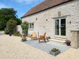 a stone cottage with a bench and a table at Bramley - Uk37378 in Pilton