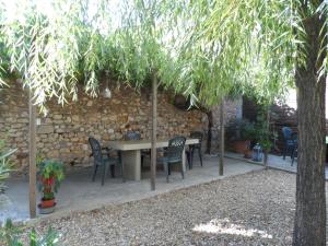 a patio with a table and chairs under a stone wall at Clos Mazerolles in Cruzy