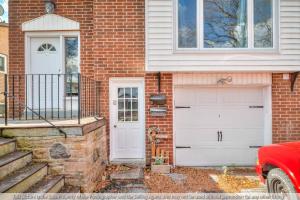 a brick house with two garage doors and a red car at Private - King Bed - Fireplace - Pets - SPA - WiFi in Whitby