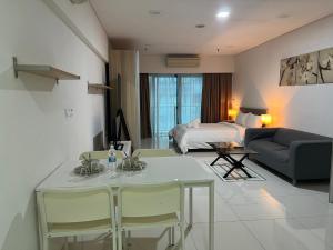 uma sala de estar com uma cama, uma mesa e cadeiras em Mercu Summer Suites Kuala Lumpur Bukit Bintang by Classy em Kuala Lumpur
