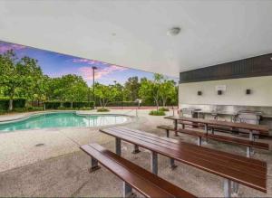 ein Gebäude mit Bänken vor einem Pool in der Unterkunft Gold Coast Theme Park4BD Family with Big Pool in Pimpama