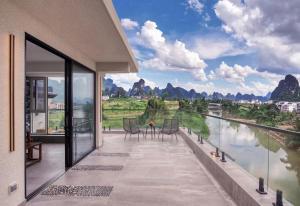 a balcony with a view of the water and mountains at Guilin Yangshuo Waterhouse River View Villa in Yangshuo